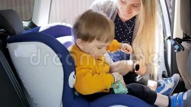 4K镜头，女人把她的孩子放在孩子的汽车安全座椅。 运输中的安全和保护